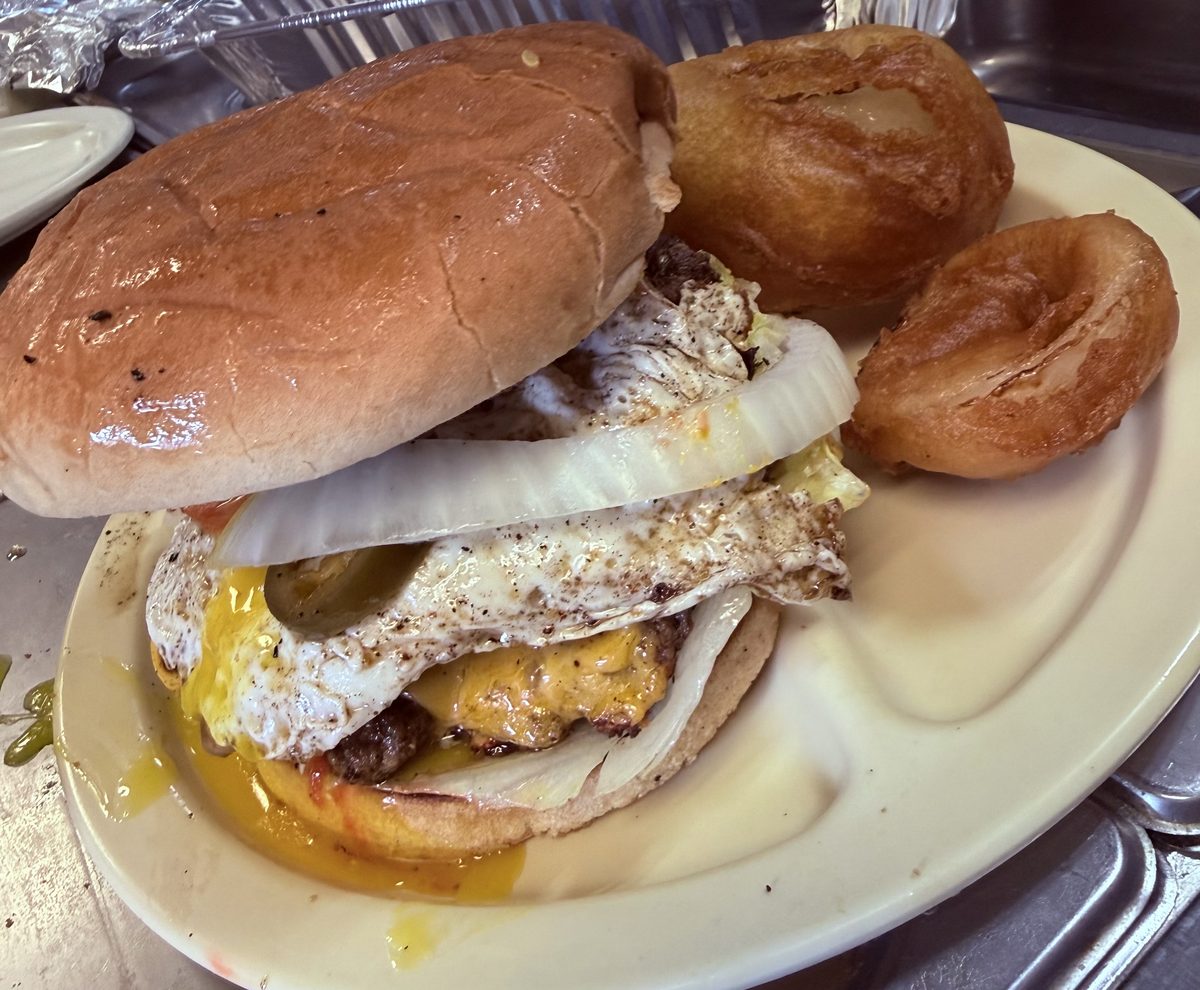 Cheeseburger topped with a fried egg and jalapeños, with onion rings